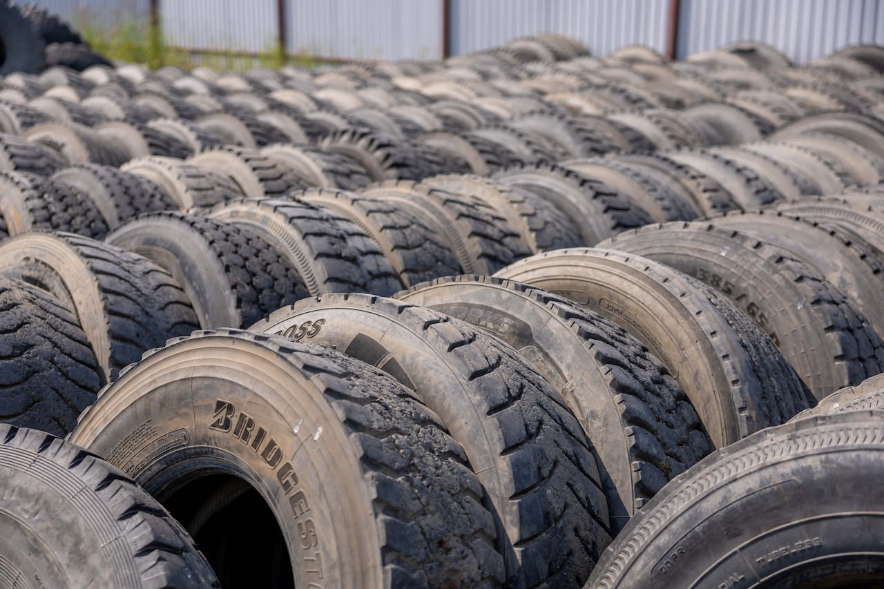 A detailed view of numerous stacked used tires in an outdoor industrial environment.